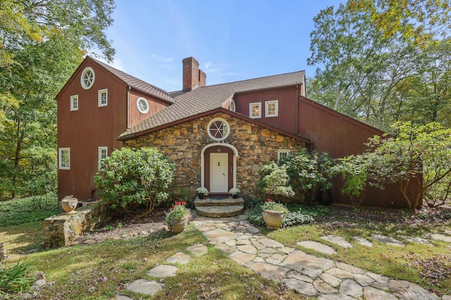 view of front facade featuring stone siding and a chimney