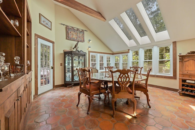 dining room with high vaulted ceiling, a skylight, and baseboards