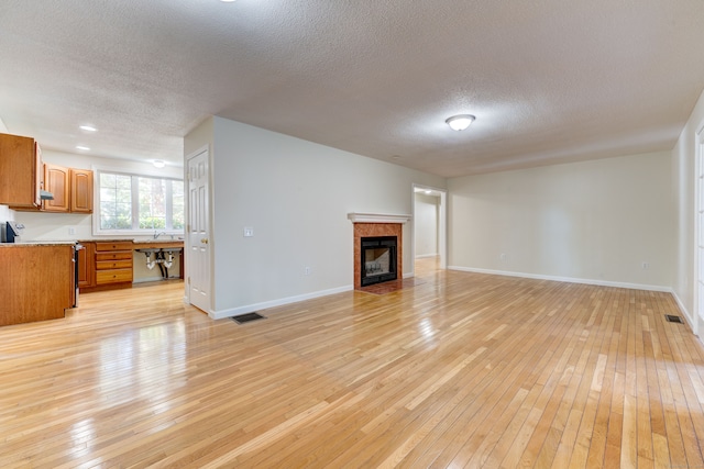 living room featuring a textured ceiling, light hardwood / wood-style flooring, and sink