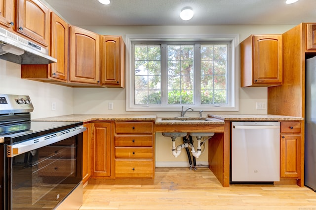 kitchen featuring a textured ceiling, sink, stainless steel appliances, and light hardwood / wood-style flooring