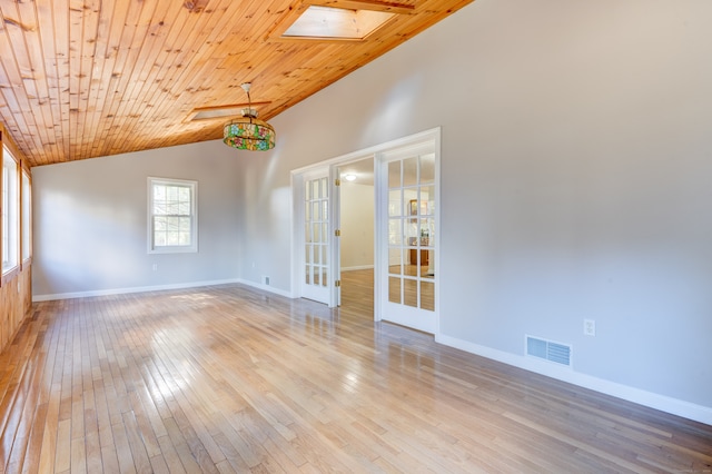 unfurnished room featuring vaulted ceiling with skylight, wooden ceiling, light hardwood / wood-style floors, and french doors