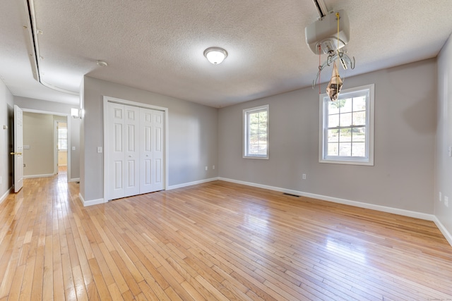 empty room featuring a textured ceiling and light hardwood / wood-style flooring