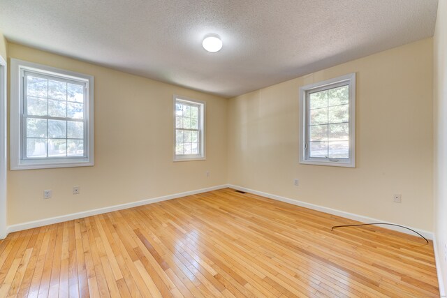 unfurnished room with plenty of natural light, wood-type flooring, and a textured ceiling