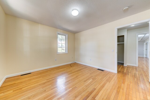 spare room featuring light wood-type flooring and a textured ceiling