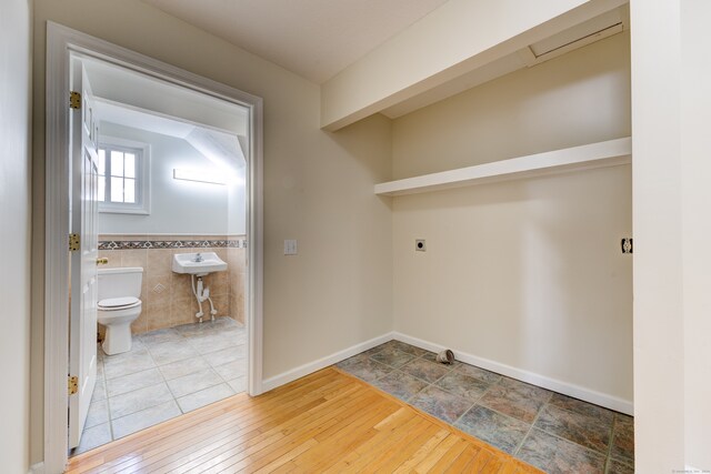 washroom featuring hardwood / wood-style flooring, tile walls, and electric dryer hookup