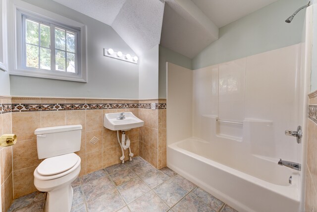 bathroom with lofted ceiling, tub / shower combination, tile walls, toilet, and a textured ceiling