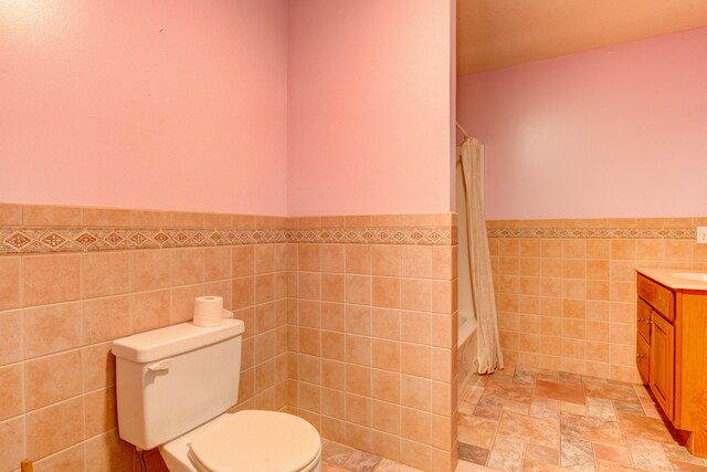 full bathroom featuring shower / bath combination with curtain, vanity, tile walls, and toilet