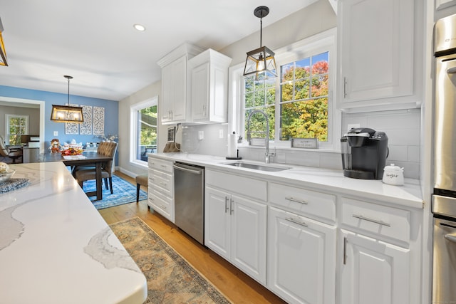 kitchen featuring pendant lighting, light hardwood / wood-style flooring, stainless steel appliances, backsplash, and white cabinets