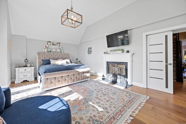 bedroom with light wood-type flooring, vaulted ceiling, and a chandelier