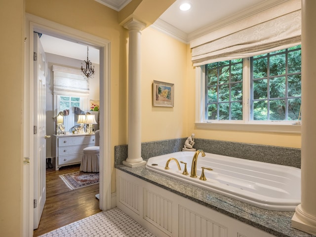 bathroom featuring decorative columns, a bathtub, crown molding, hardwood / wood-style flooring, and a notable chandelier