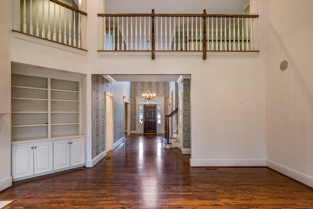 entrance foyer with a chandelier, a high ceiling, and dark wood-type flooring