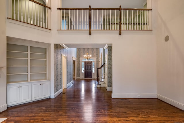 entryway with a towering ceiling, dark hardwood / wood-style floors, and a chandelier