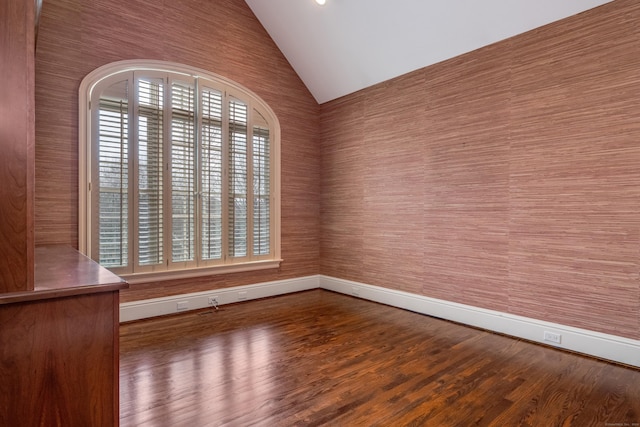 spare room featuring lofted ceiling, plenty of natural light, and dark hardwood / wood-style floors