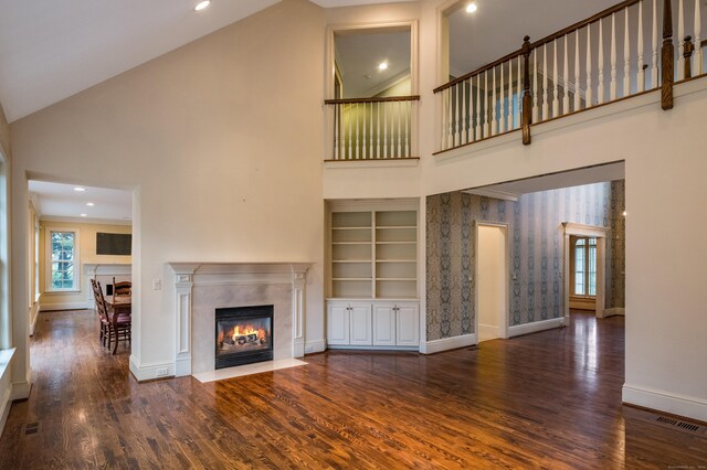 unfurnished living room featuring built in features, high vaulted ceiling, and dark wood-type flooring