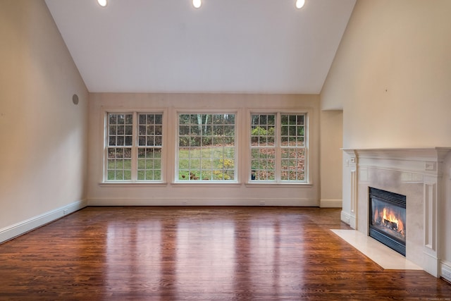 unfurnished living room with high vaulted ceiling, wood-type flooring, and a high end fireplace