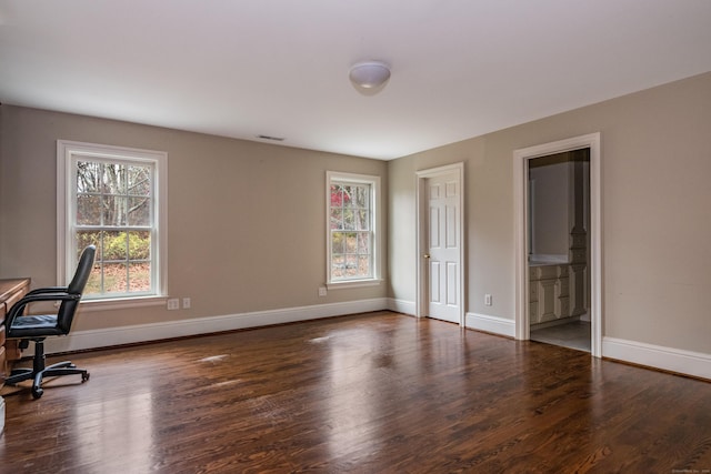 unfurnished office featuring plenty of natural light and dark hardwood / wood-style floors