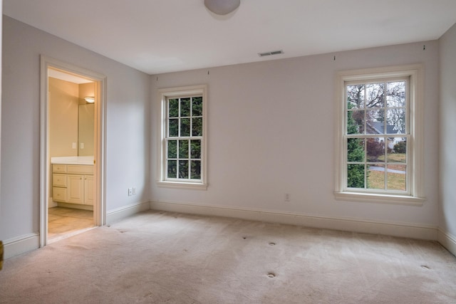 unfurnished bedroom with connected bathroom and light colored carpet