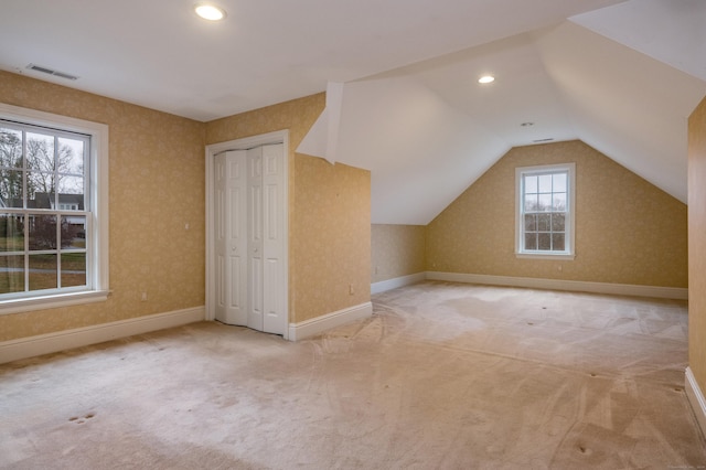 bonus room with lofted ceiling and light carpet