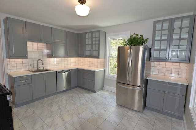 kitchen featuring gray cabinetry, sink, stainless steel appliances, and tasteful backsplash