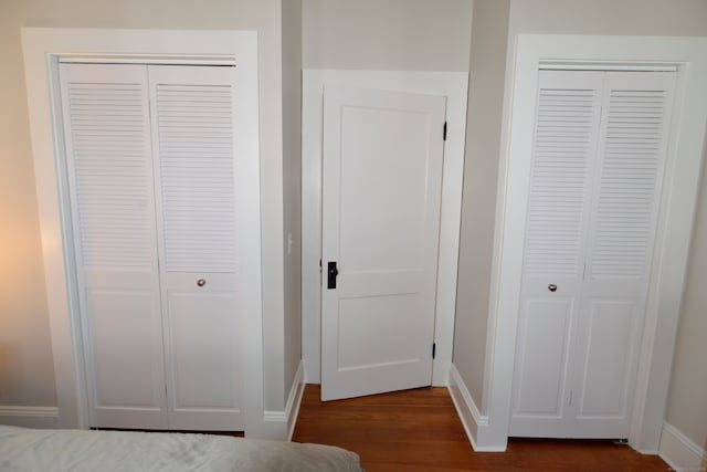 unfurnished bedroom featuring multiple closets and dark hardwood / wood-style floors