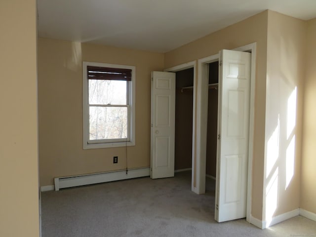 unfurnished bedroom with a baseboard heating unit, light carpet, and baseboards