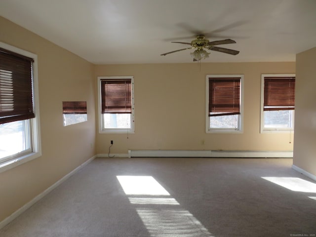 carpeted spare room with a baseboard heating unit, ceiling fan, and baseboards