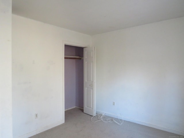 unfurnished bedroom with baseboards, a closet, and light colored carpet