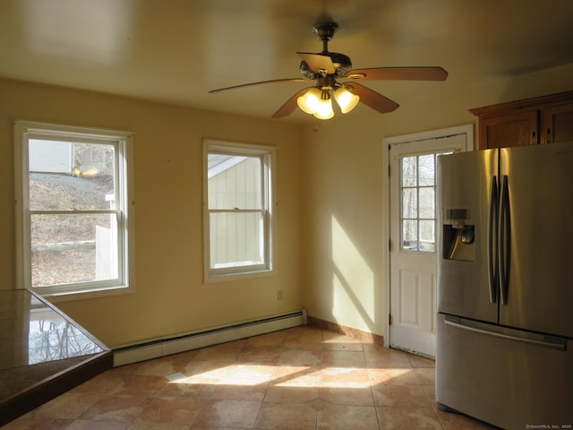 interior space featuring ceiling fan, a baseboard radiator, baseboards, brown cabinets, and stainless steel fridge