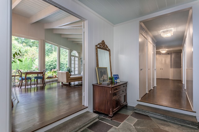 hallway featuring beamed ceiling, ornamental molding, wooden walls, dark hardwood / wood-style floors, and a notable chandelier