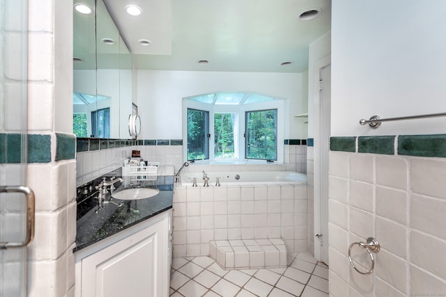 bathroom with vanity, tiled bath, tile walls, and tile patterned flooring