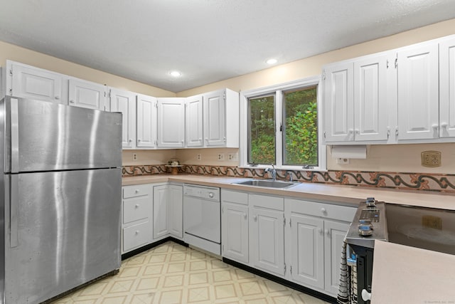 kitchen with white dishwasher, stainless steel fridge, sink, and white cabinetry