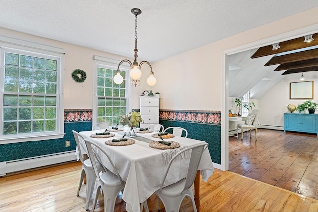 dining room with light hardwood / wood-style floors, a textured ceiling, a baseboard radiator, vaulted ceiling with beams, and a notable chandelier