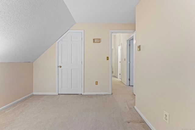 additional living space featuring light carpet, a textured ceiling, and lofted ceiling