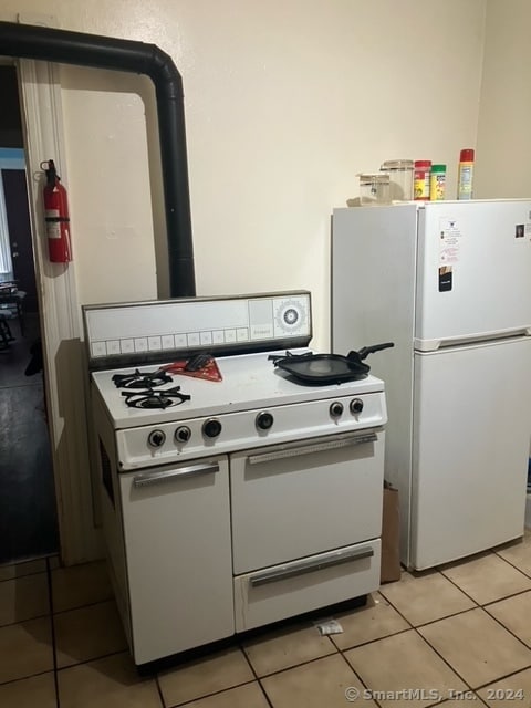 kitchen with white appliances and light tile patterned flooring