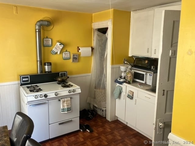 kitchen with white appliances, white cabinetry, and dark parquet floors