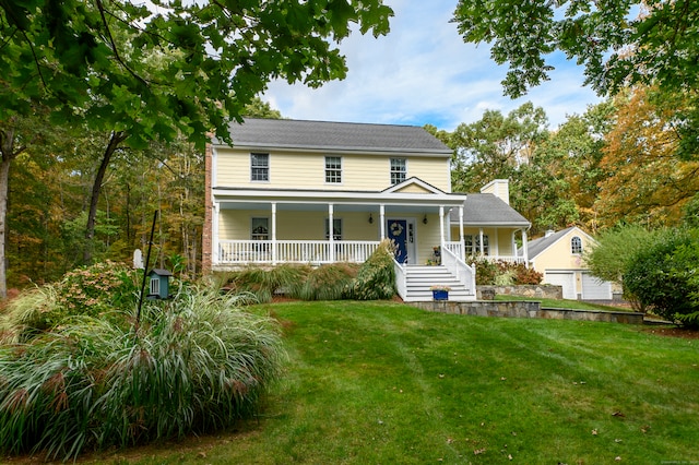 view of front of house with a garage, a front yard, a porch, and an outbuilding