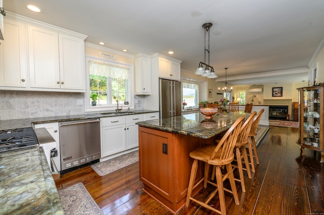 kitchen featuring stainless steel appliances, white cabinets, a healthy amount of sunlight, and dark hardwood / wood-style flooring