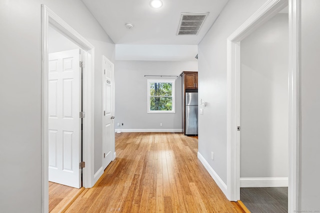 hall with light wood-style floors, visible vents, and baseboards