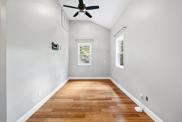 empty room with baseboards, lofted ceiling, and light wood-style floors