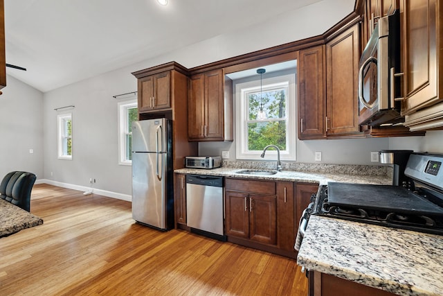 kitchen featuring appliances with stainless steel finishes, a healthy amount of sunlight, a sink, and light wood-style flooring