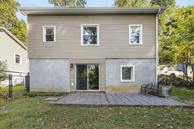 rear view of house with a yard, a patio area, fence, and stucco siding