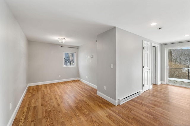 spare room with a wealth of natural light, a baseboard radiator, and light wood-style floors