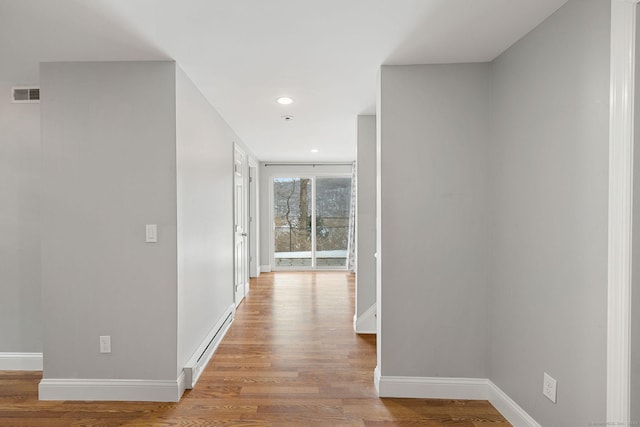 hall with light wood finished floors, recessed lighting, visible vents, a baseboard heating unit, and baseboards