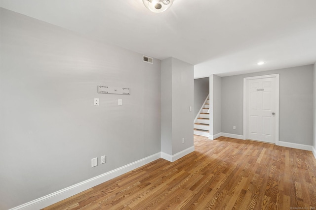 spare room featuring light wood-style floors, baseboards, stairway, and visible vents