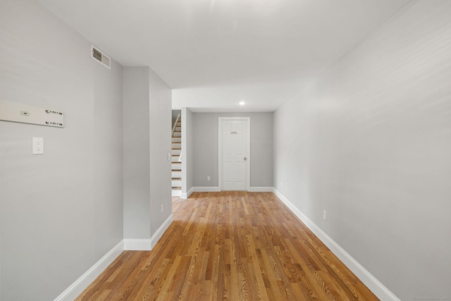 hall featuring baseboards, stairs, visible vents, and wood finished floors