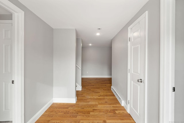 hall featuring light wood-style floors, baseboards, baseboard heating, and recessed lighting