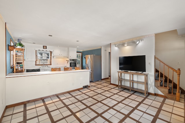 kitchen featuring appliances with stainless steel finishes, sink, kitchen peninsula, white cabinetry, and light tile patterned floors