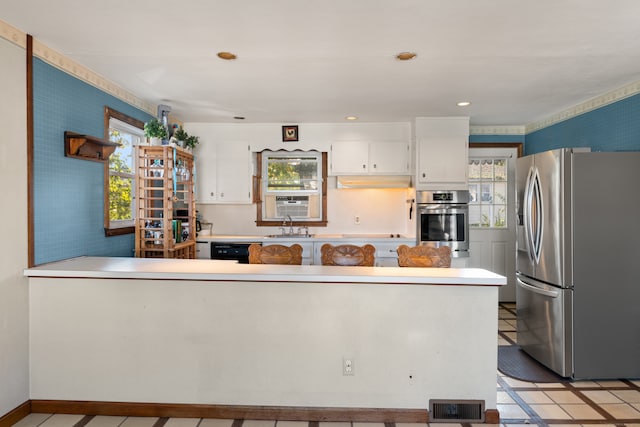 kitchen featuring sink, appliances with stainless steel finishes, kitchen peninsula, and white cabinets