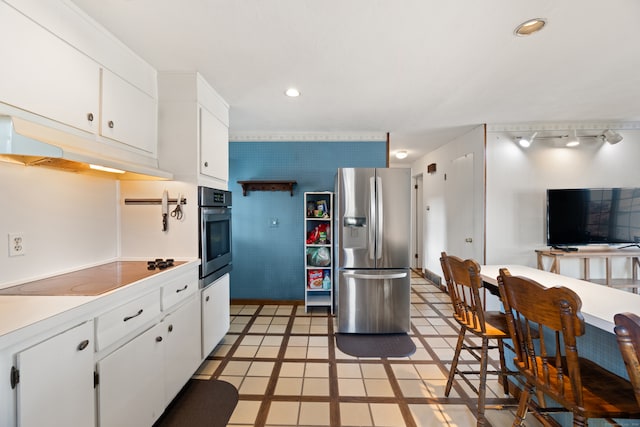 kitchen with appliances with stainless steel finishes, white cabinets, and light tile patterned flooring