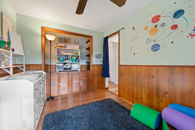 interior space featuring wooden walls, wood-type flooring, and ceiling fan